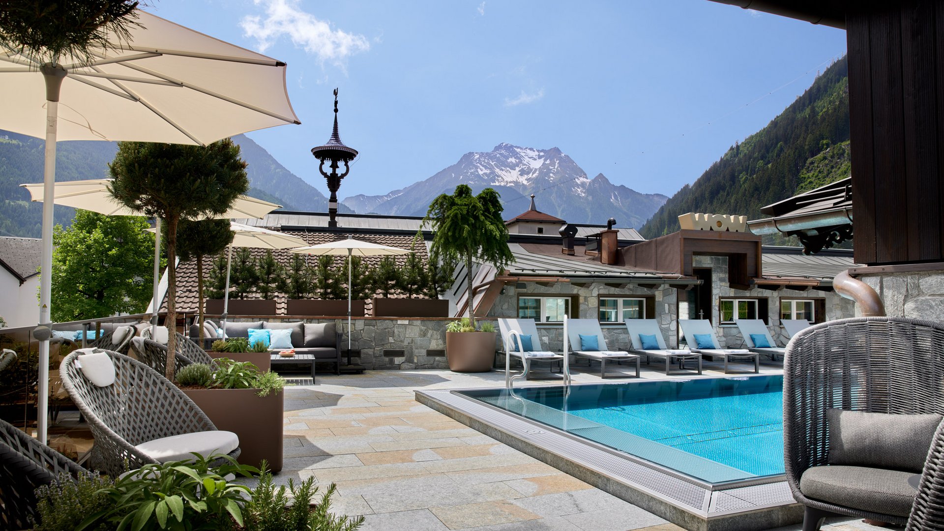 Poolbereich mit Liegestühlen und Bergen im Hintergrund an einem sonnigen Tag